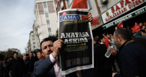 Un uomo con una copia dell'edizione di sabato di Zaman, con il titolo “Costituzione sospesa”, durante una manifestazione fuori dagli uffici del giornale a Istanbul. (AP Photo/Emrah Gurel)